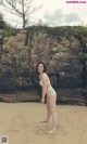 A woman in a white bikini standing on a sandy beach.