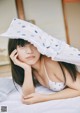 A woman laying on a bed with a hat over her head.