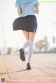 A woman in a blue shirt and black skirt is walking down the street.