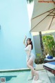 A woman in a white bikini standing next to a pool.