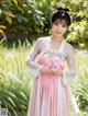 A woman in a pink and white hanbok standing in a field.